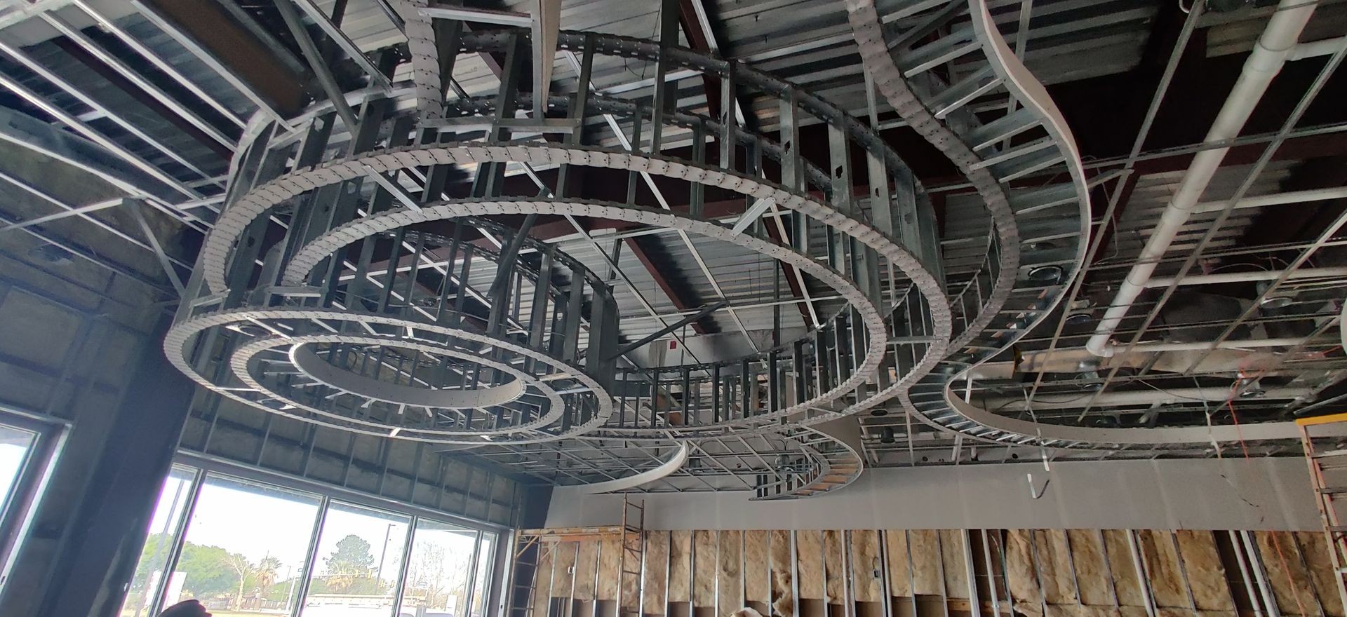 Suspended metal framework for circular structures on the ceiling of an unfinished building.